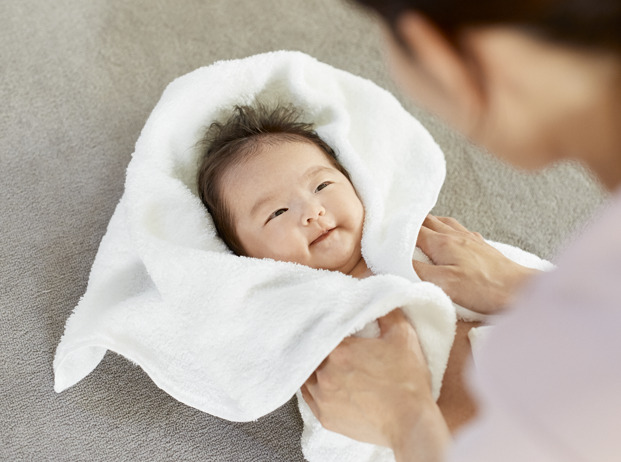 バスタオルで水分を拭き取ってもらっている赤ちゃん