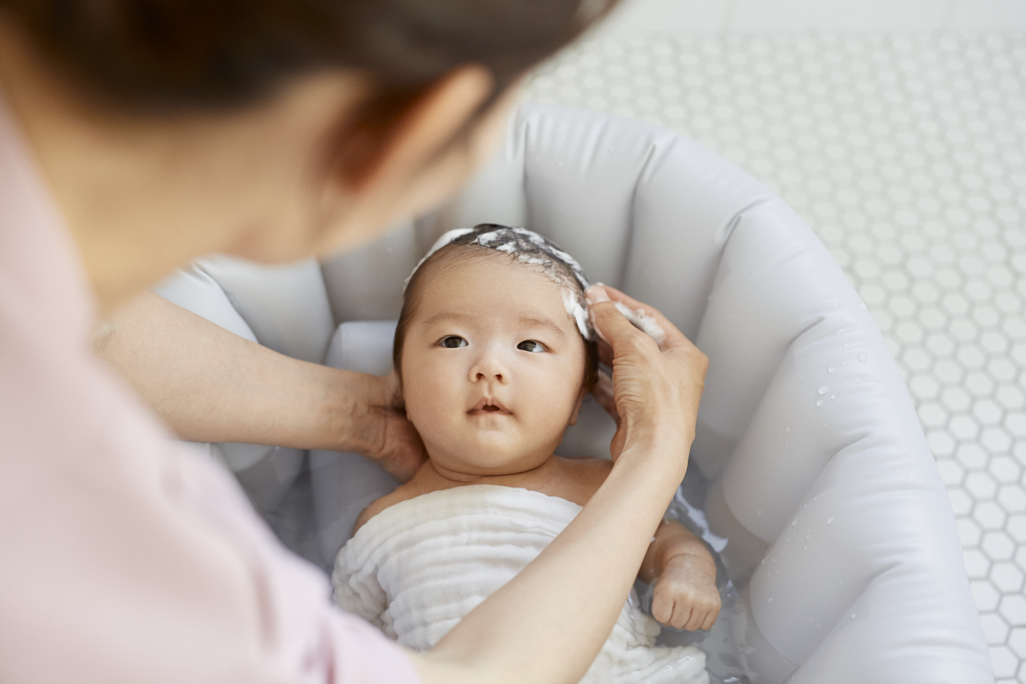 沐浴で頭を洗ってもらっている赤ちゃん
