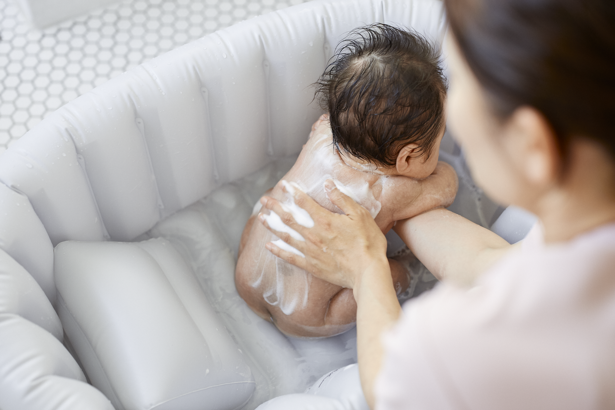 沐浴で背中を洗ってもらっている赤ちゃん